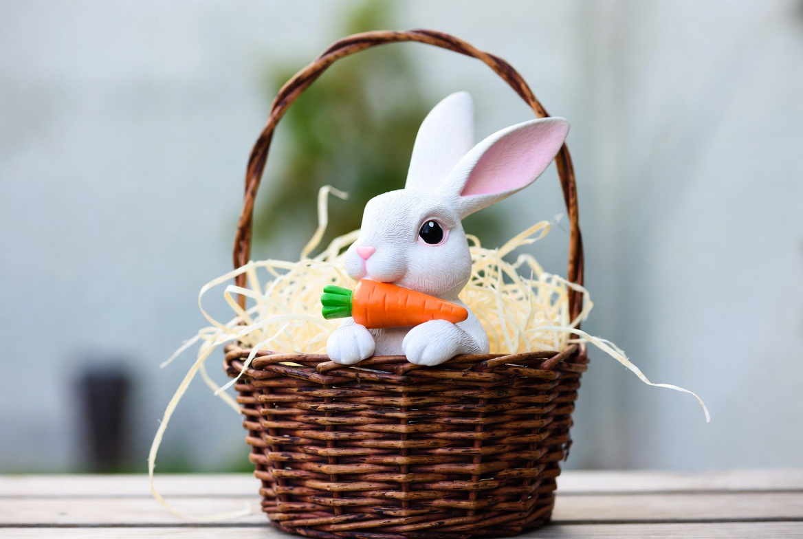 White bunny holding carrot in Easter basket White bunny holding carrot in Easter basket