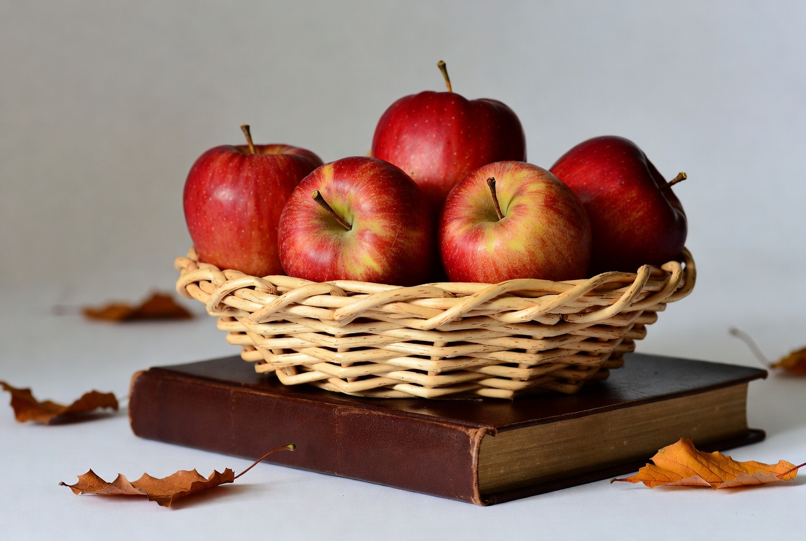 Red Apples in Wicker Basket on Book Red Apples in Wicker Basket on Book