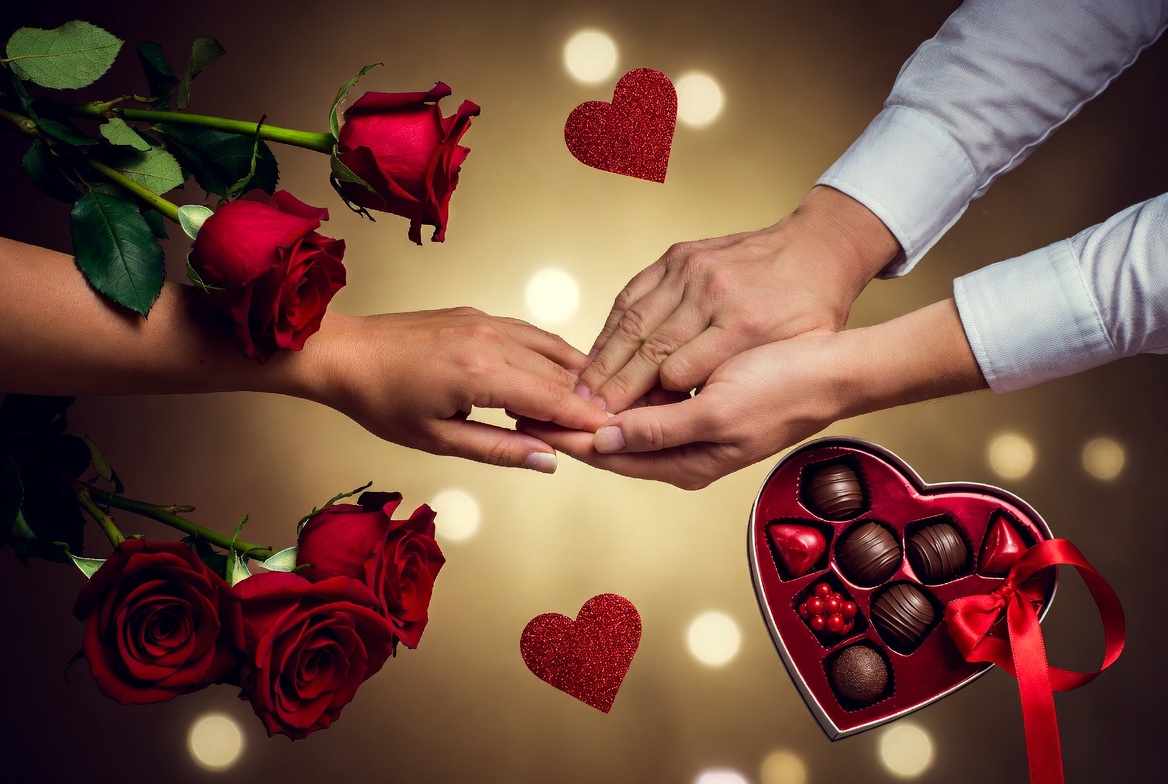 Couple's hands holding chocolates and roses Couple's hands holding chocolates and roses