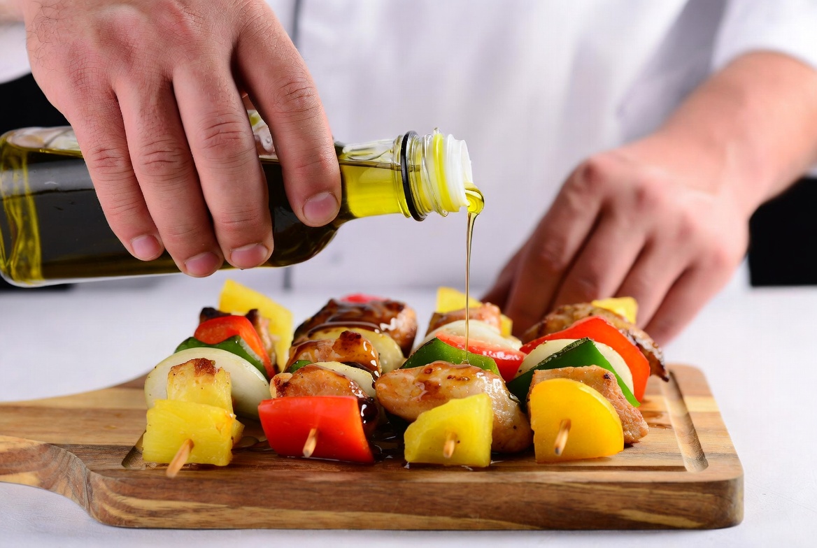 Chef drizzling oil on chicken skewers Chef drizzling oil on chicken skewers