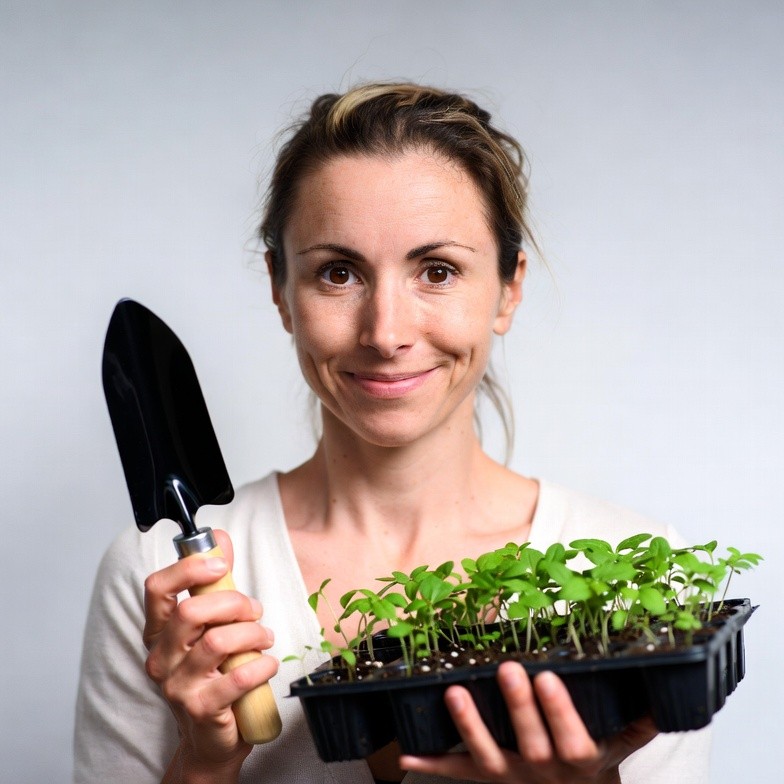 Woman holding seedlings and trowel Woman holding seedlings and trowel