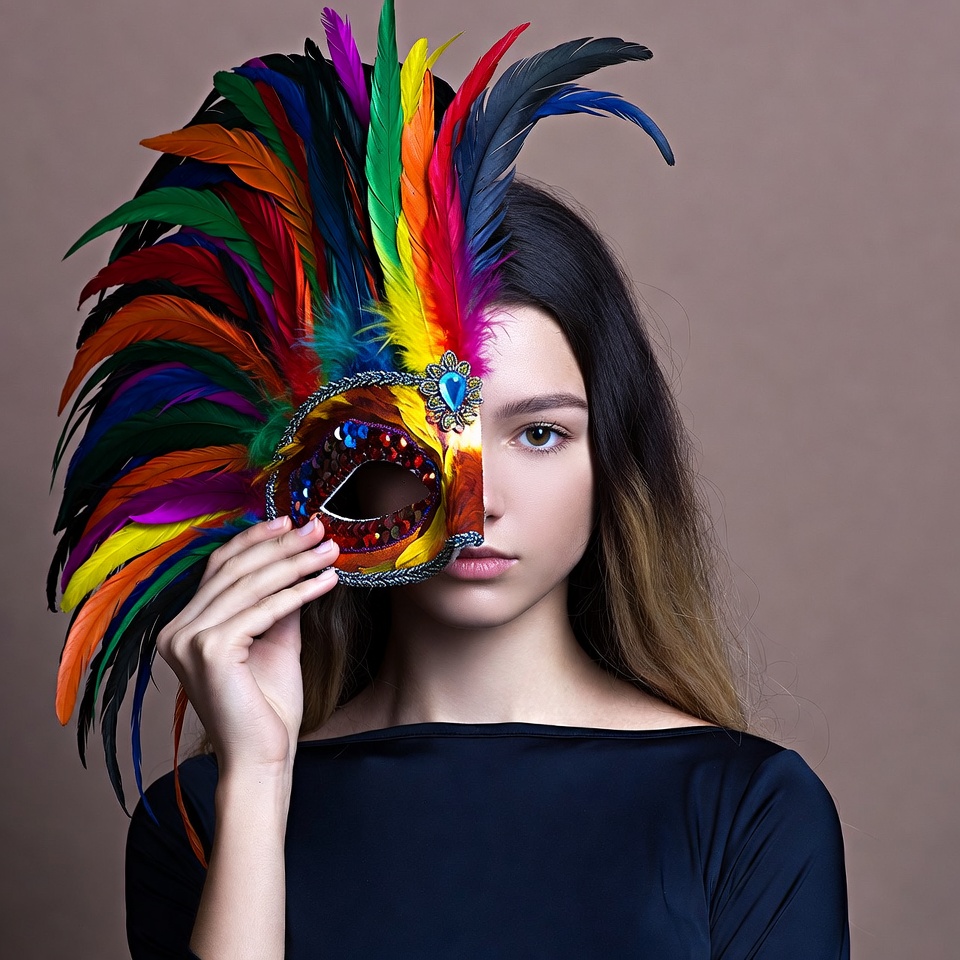 Woman holding colorful feathered mask Woman holding colorful feathered mask