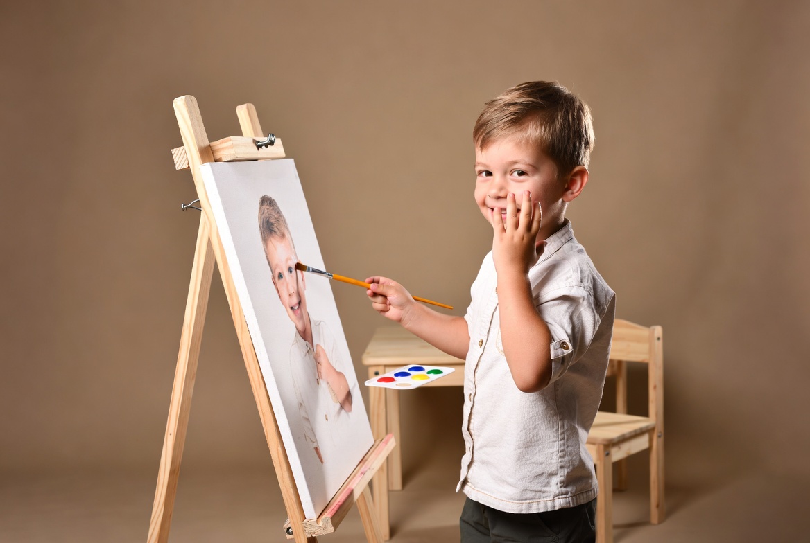 Boy painting self-portrait on easel Boy painting self-portrait on easel