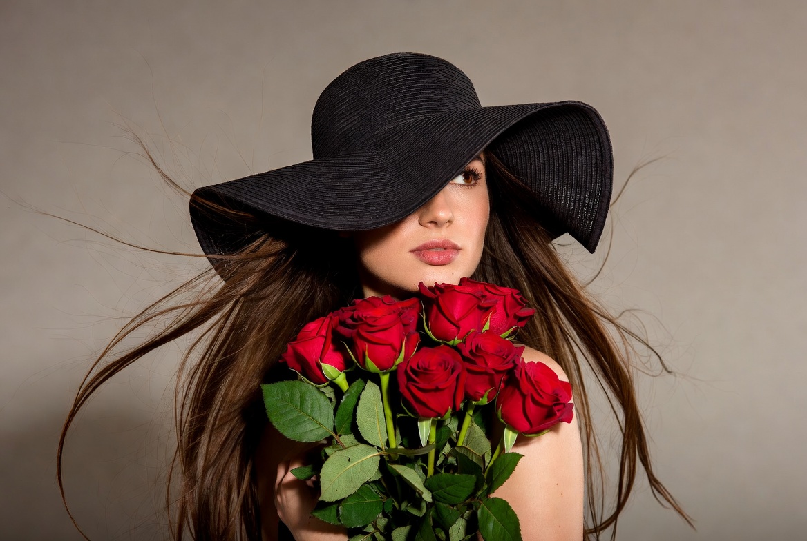 Woman holding red roses with wide-brim hat Woman holding red roses with wide-brim hat