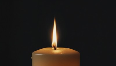 Single candle flame in darkness