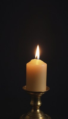 Single candle burning on brass candlestick