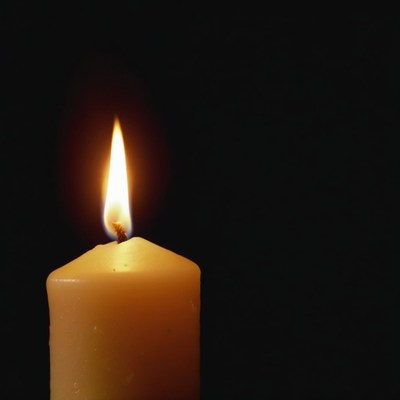 Single candle flame in darkness