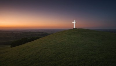 Cross on hilltop at sunset