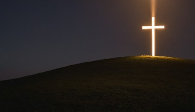 Illuminated cross on hilltop at night