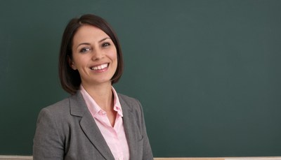 Woman smiling in front of green chalkboard
