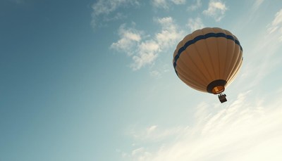 A yellow hot air balloon floats through the clouds