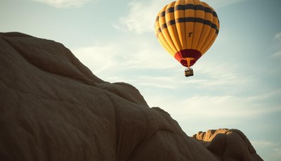 A yellow hot air balloon floats above a rocky landscape