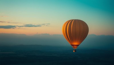 A hot air balloon floats over the mountains at sunrise