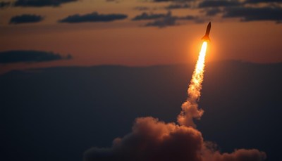 A rocket launches into the evening sky
