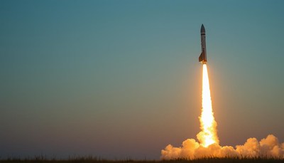 A rocket launches into the sky at dusk