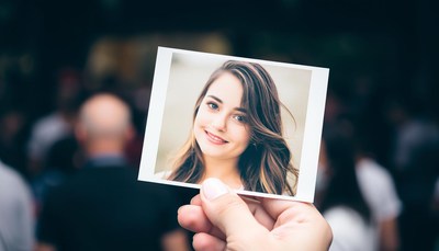 A hand holds a photo of a woman smiling