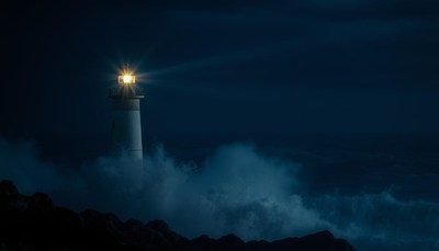 A lighthouse shines brightly in the night