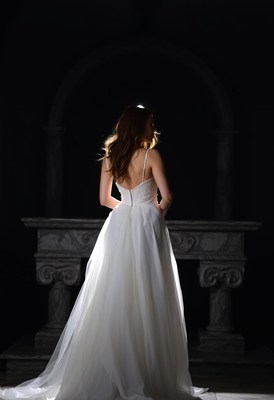 A woman in a white dress stands in a dark room