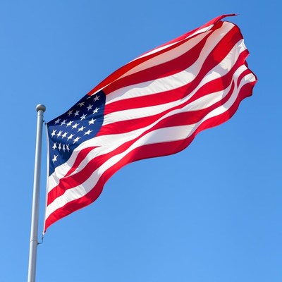 The american flag waves in the wind against a clear blue sky