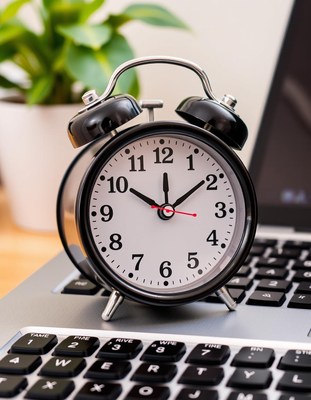 An alarm clock sits on a laptop keyboard