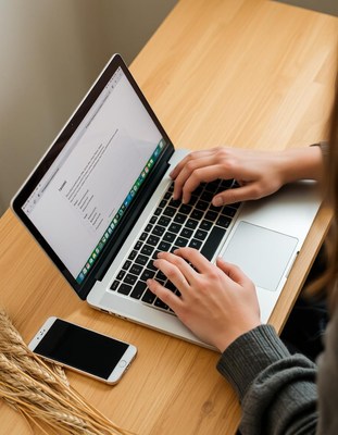A person types on a laptop at a desk