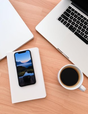 Phone on notebook by laptop and coffee on desk