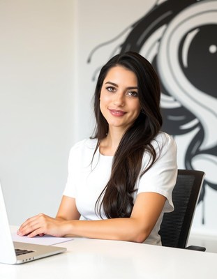 A woman smiles while working on her laptop