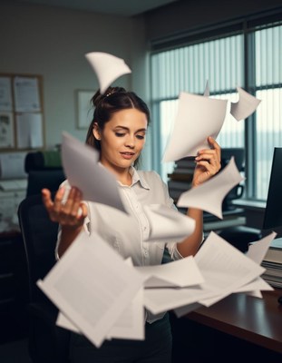 A woman throws papers in the air at her desk