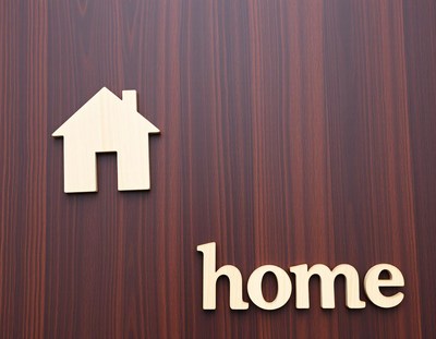 A wooden home cutout on a dark wood background