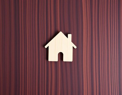 A wooden house cutout on a woodgrain background