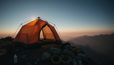 A tent sits atop a mountain at sunset