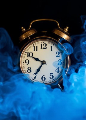 Old alarm clock in blue smoke, set near 10