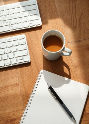 Coffee on a desk with a notebook and pen
