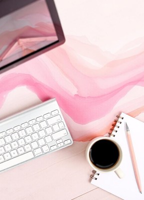A keyboard, notebook, and coffee on a pink desk