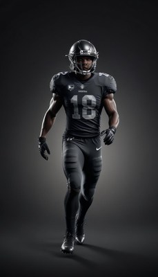 A football player in black uniform walks towards the camera