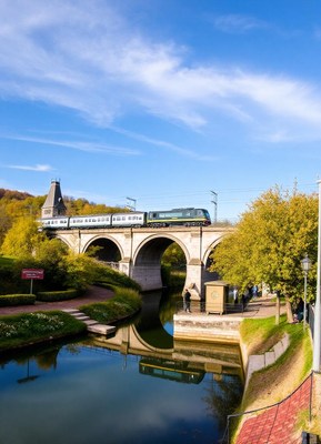 A train crosses a bridge over a canal in a park