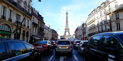 Cars drive past the eiffel tower in paris