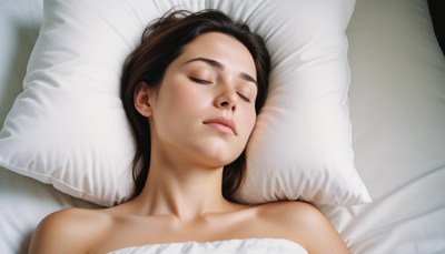 A woman sleeps peacefully on a white pillow