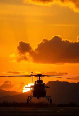 A helicopter sits on a runway at sunset