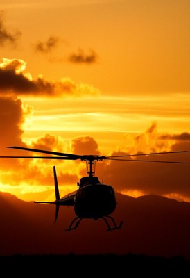 A helicopter flies into the sunset