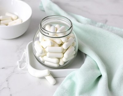 White capsules in a glass jar on a white counter