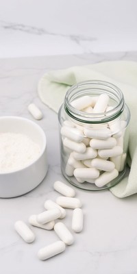 White capsules in a glass jar on a marble countertop
