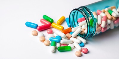 Colorful pills spill out of a blue bottle
