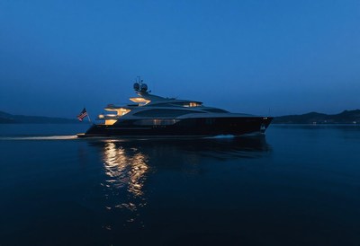 A large yacht sails past an island at night