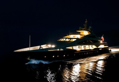 A large yacht cruises through the water at night