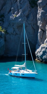 A sailboat is docked in a cove with tall cliffs