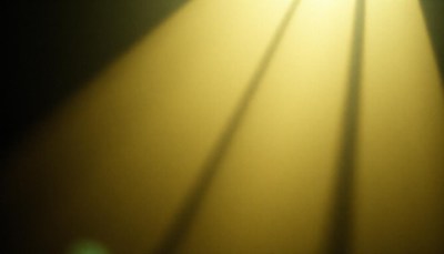 A blurry yellow spotlight casts shadows on a wall