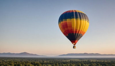 A hot air balloon floats over the landscape at sunrise