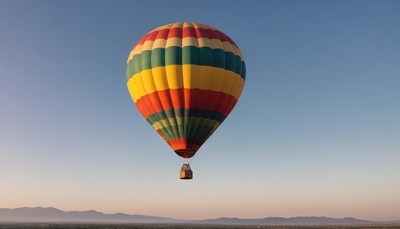 A colorful hot air balloon floats in the sky at sunrise