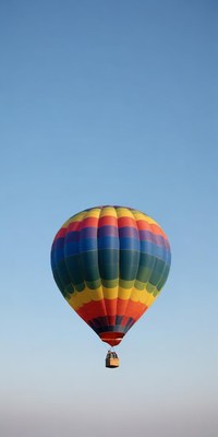 A colorful hot air balloon floats in a blue sky